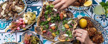 Hands reach for a Middle Eastern feast