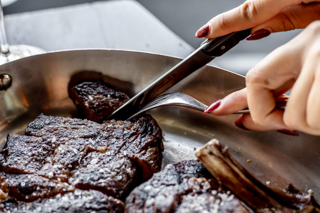 A woman cuts into a steak in a metal pan